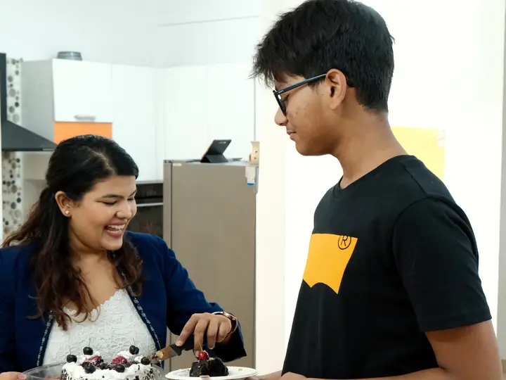 Sona serving a slice of cake to a guest at the studio