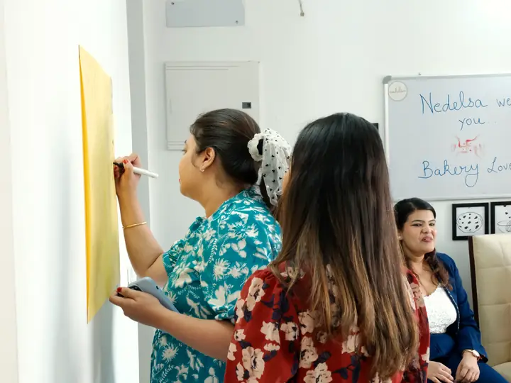 Two guests writing messages on the studio wish board
