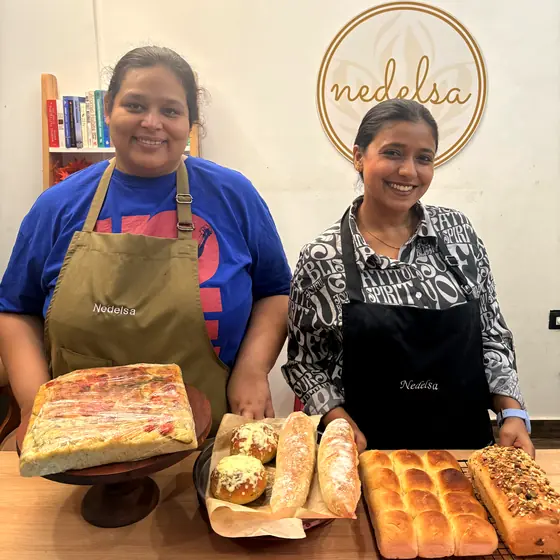 Two students behind a table of focaccia, baguettes and seeded loaves they have baked