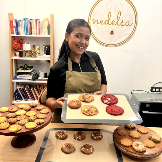 A student presenting a tray of red velvet and chocolate chip cookies she has baked