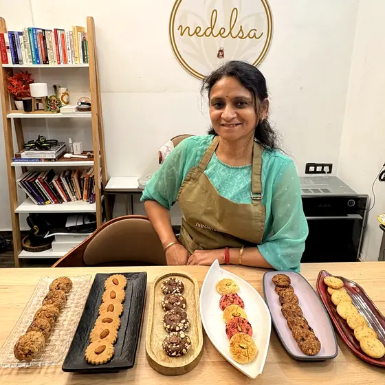 A student standing behind six trays of different cookies at the end of a class