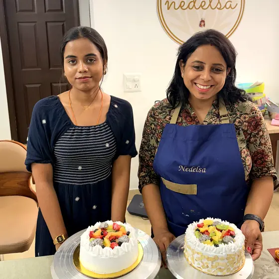 Two students standing behind the fresh fruit cream cakes they have finished