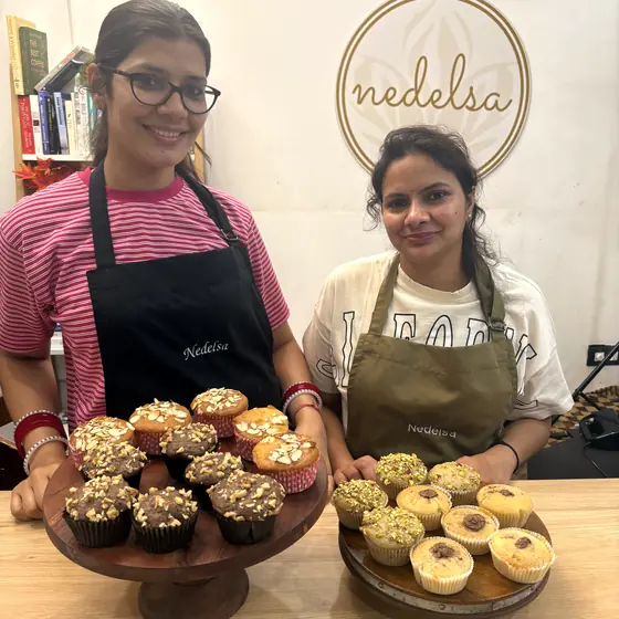Two students holding wooden stands of walnut and pistachio muffins